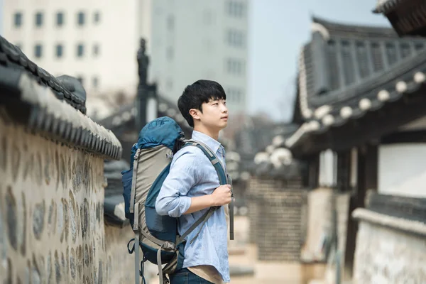 Kore geleneksel evde bir sırt çantasıyla yolculuk yapan genç erkek. — Stok fotoğraf