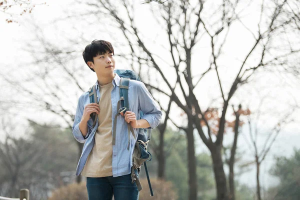 Kore geleneksel evde bir sırt çantasıyla yolculuk yapan genç erkek.