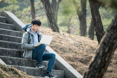 Dizüstü bilgisayar kullanarak backpacking Asyalı adam