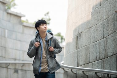 Kore geleneksel evde bir sırt çantasıyla yolculuk yapan bir genç erkek.