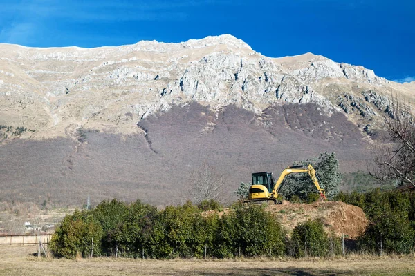 stock image excavator under mountain