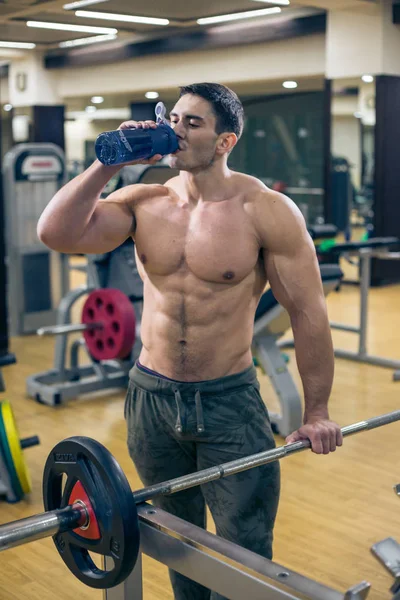 Bodybuilder trinkt Wasser. Spaß in der Sporthalle. Gesunder Lebensstil. — Stockfoto