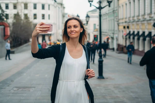 Hermosa chica hace foto en la ciudad europea. Selfie está en Moscú. Chica hace selfie en la calle . — Foto de Stock