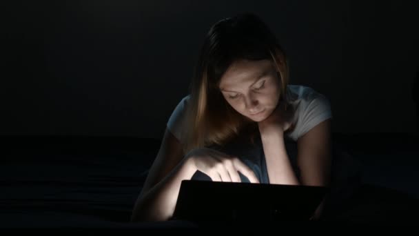 Hermosa chica utiliza tableta en un dormitorio — Vídeos de Stock