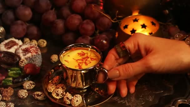 차를 마시는 그리고 전통적인 모로코 과자 먹는 동양 귀고리와 여자. 사프란 Masala 우유 차 한잔 — 비디오