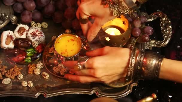 Mujer con joyas orientales bebiendo té y comiendo dulces tradicionales marroquíes. Taza de té de leche de azafrán Masala — Vídeos de Stock