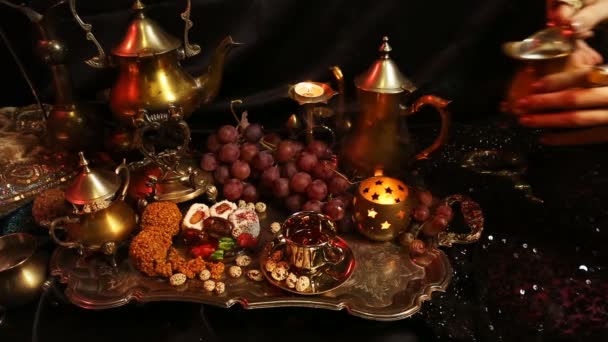 Mãos femininas com jóias orientais derramando chá na xícara. Doces marroquinos tradicionais. Xícara de chá de leite Saffron Masala — Vídeo de Stock