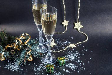Noel havası. Şampanya ile bardaklar. Yeni yıl. Noel ağacı süslemeleri, kozalaklı dallar. Boşluğu kopyala. 