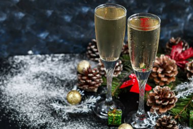 Noel havası. Şampanya ile bardaklar. Yeni yıl. Noel ağacı süslemeleri, kozalaklı dallar. Boşluğu kopyala. 