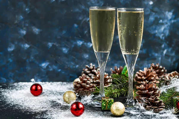 Noel havası. Şampanya ile bardaklar. Yeni yıl. Noel ağacı süslemeleri, kozalaklı dallar. Boşluğu kopyala. 