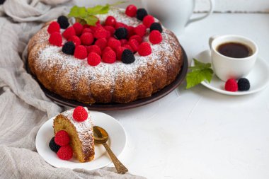 Noel, üzerine pudra şekeri serpiştirilmiş tatil pastası. Ahududu ve böğürtlenli. Yakınlarda bir fincan sıcak kahve var. Beyaz arka planda. Boşluğu kopyala. 