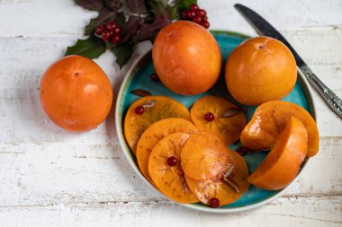 Plakada hurma, arka planda hafif bir şey. Kış meyvesi Sağlıklı beslenme turuncu rengi. Boşluğu kopyala. 