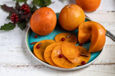 Plakada hurma, arka planda hafif bir şey. Kış meyvesi Sağlıklı beslenme turuncu rengi. Boşluğu kopyala. 