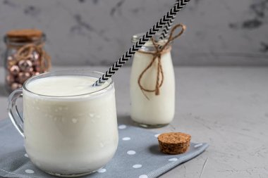 Kefir, probiyotiklerle mayalanmış bir içecek. Faydalı ve modaya uygun ekşi süt yiyecekler ve içecekler. Hafif arkaplan. Kağıt tüp. Boşluğu kopyala. 