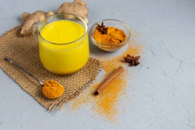 Baharatlı altın süt. Zerdeçal, karanfil, karabiber ve bir damla bitkisel yağ. Geleneksel Hint içkisi. Hafif bir arkaplanda. Sağlıklı yeme alanı kopyala. 