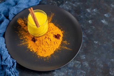 Bardakta sütlü sütlü sağlıklı zerdeçal içeceği. Safranlı altın süt, zencefil kökü, tarçın çubuğu ve koyu arkaplanda bal. Detoks çayı. Sağlıklı yeme alanı kopyala. 