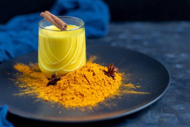 Bardakta sütlü sütlü sağlıklı zerdeçal içeceği. Safranlı altın süt, zencefil kökü, tarçın çubuğu ve koyu arkaplanda bal. Detoks çayı. Sağlıklı yeme alanı kopyala. 