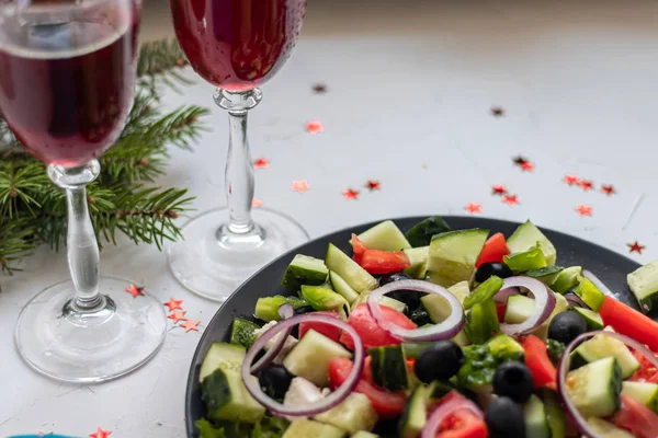 Greek salad. Diced tomatoes, cucumbers, feta cheese, olives. Rings of red onion. Food for vegetarians. Festive and New Year\'s dish. On a light background. Copy space.
