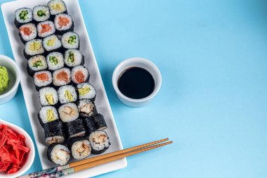 Balıklı suşi, salatalık, yılan balığı, avokado. Nori Seaweed 'e sarılmış. Vejetaryenler için yemek. Soya sosu, zencefil, beyaz kaselerde wasabi. Boşluğu kopyala.