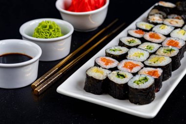 Balıklı suşi, salatalık, yılan balığı, avokado. Nori Seaweed 'e sarılmış. Vejetaryenler için yemek. Soya sosu, zencefil, beyaz kaselerde wasabi. Boşluğu kopyala.