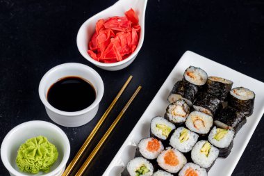 Balıklı suşi, salatalık, yılan balığı, avokado. Nori Seaweed 'e sarılmış. Vejetaryenler için yemek. Soya sosu, zencefil, beyaz kaselerde wasabi. Boşluğu kopyala.