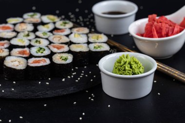 Balıklı suşi, salatalık, yılan balığı, avokado. Nori Seaweed 'e sarılmış. Vejetaryenler için yemek. Soya sosu, zencefil, beyaz kaselerde wasabi. Boşluğu kopyala.