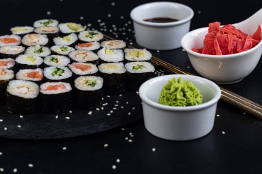 Balıklı suşi, salatalık, yılan balığı, avokado. Nori Seaweed 'e sarılmış. Vejetaryenler için yemek. Soya sosu, zencefil, beyaz kaselerde wasabi. Boşluğu kopyala.