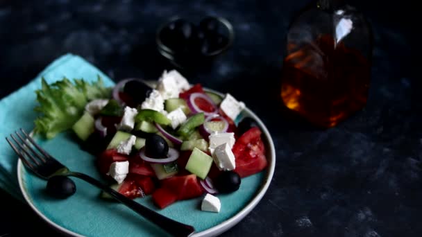 Vařím řecký salát. Na zeleném talíři rozetřeme rajčata, okurky, nakrájíme na plátky. Prsteny červené cibule. Vegetariánské jídlo. Zdravé stravování 