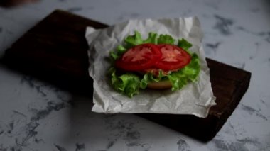 Evde hamburger pişiriyorum. Aşamalı yerleşim. Tavuk pirzolası, soğan, sebze, krem peynir ve marullu büyük aperatif burger..
