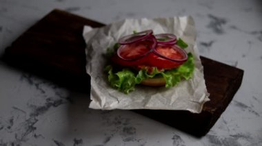 Evde hamburger pişiriyorum. Aşamalı yerleşim. Tavuk pirzolası, soğan, sebze, krem peynir ve marullu büyük aperatif burger..