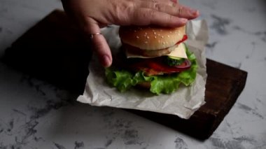 Evde hamburger pişiriyorum. Aşamalı yerleşim. Tavuk pirzolası, soğan, sebze, krem peynir ve marullu büyük aperatif burger..