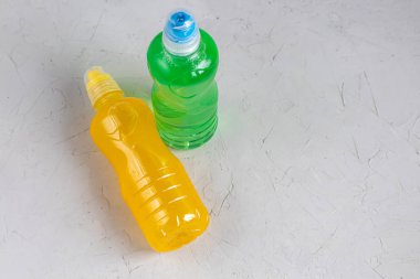 Sağlıklı bir diyet için taze meyve suyu. İzotonik, enerji içeceği. İki renkli su şişesi, bir spor içeceği. Su dengesini sağlıyor. Boşluğu kopyala. 