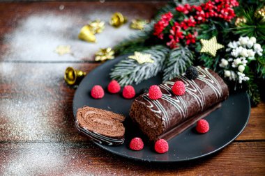 Dilimlenmiş çikolata rulosu. Çilekle süslenmiş. Uzayı kopyala Noel, yeni yıl havası. Bir fincan kahveyle kahvaltı.. 