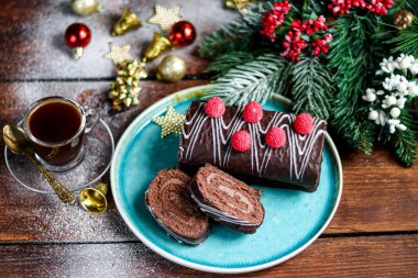 Dilimlenmiş çikolata rulosu. Çilekle süslenmiş. Uzayı kopyala Noel, yeni yıl havası. Bir fincan kahveyle kahvaltı.. 