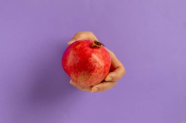 Dişi el, bir nar tutar. Bir kağıt parçasıyla deliğe sokulmuş. Sağlıklı yeme alanı kopyala. 