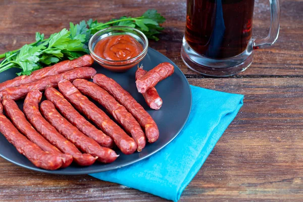 Salchichas ahumadas en un plato oscuro. Cerca de un gran vaso de cerveza oscura. Copiar espacio . — Foto de Stock