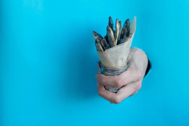 Çizim kağıdının deliğinde bir el bir kova tuzlu, küçük balık tutar..