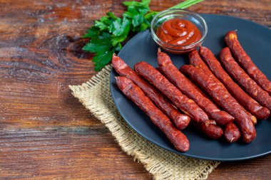 Siyah tabakta füme sosis. Büyük bir bardak koyu biranın yanında. Boşluğu kopyala.