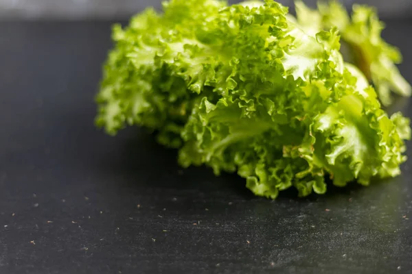 Green lettuce on a dark background. Healthy and healthy food. Can be added to vegetarian salads.
