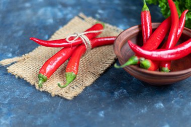 Betonun altında koyu bir arka planda acı kırmızı biber. Baharatlı gıda takviyesi.