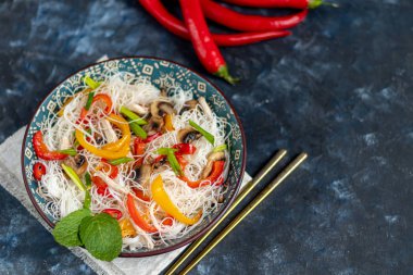 Doğu usulü pirinç eriştesi, Udon, tatlı biber ve mantar. Karanlık bir arka planda.