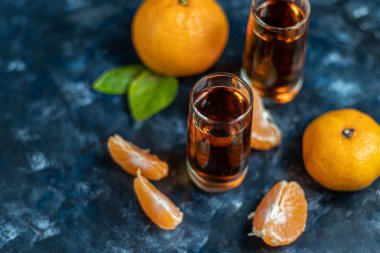 Karanlık bir arka planda gözlüklü konyak. Mandalina yakınlarında. Şenlik havası.