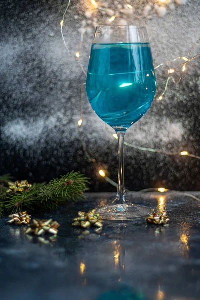 Blauwe wijn in een glas op een donkere achtergrond. Op de achtergrond bokeh van de lichten. Feestelijke stemming. — Stockfoto
