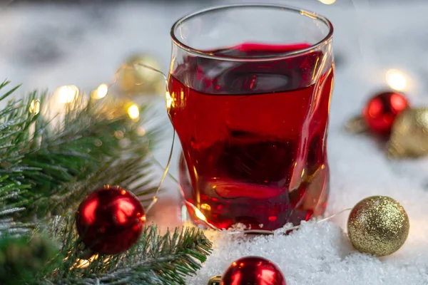 Bicchiere trasparente con una bevanda festiva. Vino rimuginato o composta. Cavalletti in neve artificiale . — Foto Stock