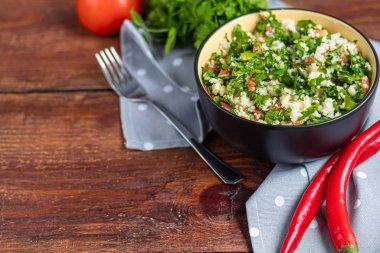 Tabbouleh salatası ahşap bir arka planda yuvarlak bir tabakta.