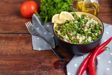 Tabbouleh salatası ahşap bir arka planda yuvarlak bir tabakta.