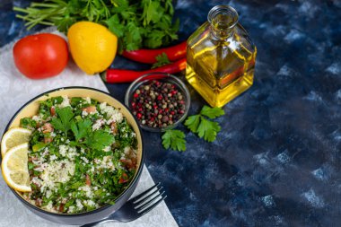 Koyu mavi arka planda yuvarlak tabakta Tabbouleh salatası.