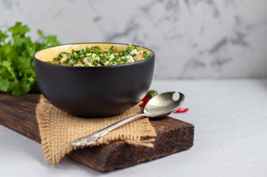 Tabbouleh salatası yuvarlak bir tabakta açık gri arka planda betonun altında.