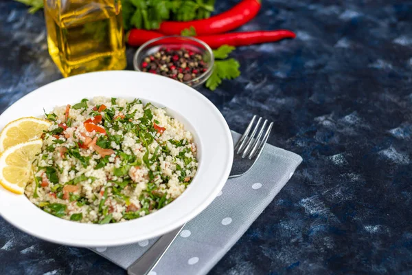 Salată de tabbouleh într-o placă albă pe un fundal albastru închis, la modă 2020 . — Fotografie, imagine de stoc