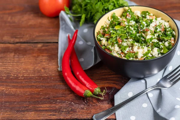 Tabbouleh-Salat in einem runden Teller auf einem hölzernen Hintergrund. — Stockfoto
